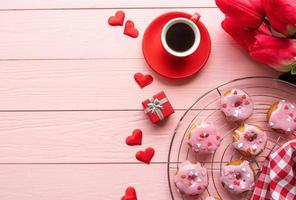 Valentijnsdag brackfast met koffie en donuts geïsoleerd op roze houten achtergrond foto