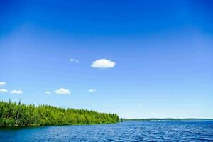 een meer met bomen en blauw lucht foto