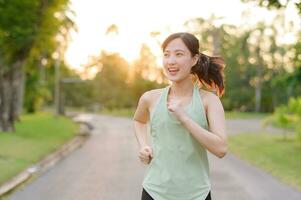 fit Aziatisch jong vrouw jogging in park glimlachen gelukkig rennen en genieten van een gezond buitenshuis levensstijl. vrouw jogger. geschiktheid loper meisje in openbaar park. gezond levensstijl en welzijn wezen concept foto