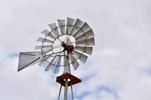 een windmolen tegen een blauw bewolkt lucht foto