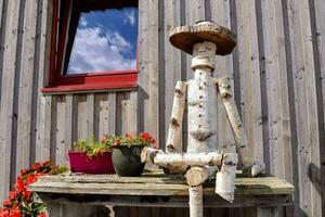 een houten Mens zittend Aan een bank met bloem potten foto