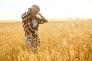 vrouw in een tarwe veld- Aan de achtergrond van de instelling zon foto