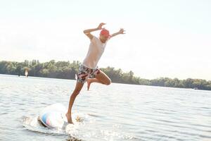 portret van een surfer met een sup bord Aan de strand. jong Mens Aan paddleboard Bij ochtendgloren. de concept van extreem sport. mannetje surfer levensstijl. foto