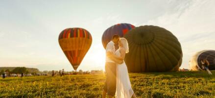 mooi romantisch paar knuffelen Bij weide. heet lucht ballon Aan een achtergrond foto