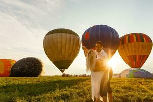 mooi romantisch paar knuffelen Bij weide. heet lucht ballon Aan een achtergrond foto