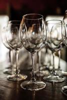 lege wijnglazen. mooie nieuwe glazen voor wijn uit glas staan in even rijen op een houten tafel in een restaurant. selectieve focus foto