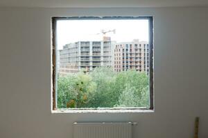 leeg kader Aan een breed panoramisch venster. prachtig visie van de venster van een appartement in een meerdere verdiepingen gebouw. daken van huizen en bomen van een hoogte. mooi visie door de venster. kader voor foto