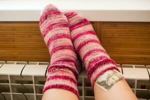 voeten in warm winter sokken warm omhoog Aan de radiator. foto