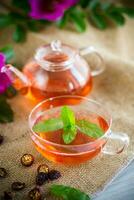 gebrouwen rozenbottel thee in een glas theepot met rozenbottel bloemen en munt foto
