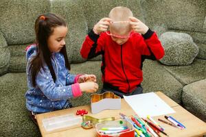 primair school- kinderen jongen en meisje zijn verloofd in creatief handgemaakt kunst Bij de tafel Bij huis foto