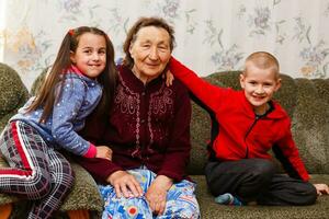 detailopname portret van gelukkig overgrootmoeder met achterkleinkinderen Aan de sofa Bij huis foto