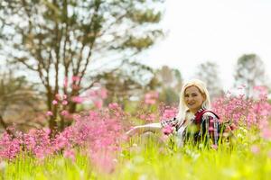 gelukkig avonturier vrouw staat Aan de groen berg helling tussen bloeiend roze rododendrons en op zoek in de afstand. episch reizen in de bergen. breed hoek. foto