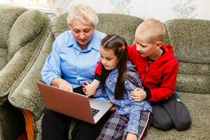 grootmoeder met kleinkinderen gebruik makend van laptop Bij huis foto