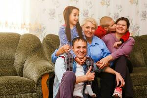 grootmoeder en kleinkinderen zittend samen Aan sofa in leven kamer foto