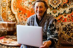 ouderling vrouw gebruik makend van een laptop computer Bij huis foto
