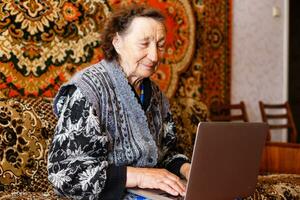 ouderling vrouw gebruik makend van een laptop computer Bij huis foto