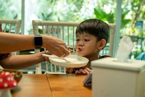 Aziatisch jongen aan het eten verwerkt voedsel gemaakt van champignons foto