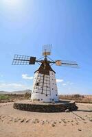 een oud windmolen in de woestijn met een blauw lucht foto