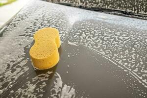 auto schoonmaak en het wassen met geel spons en schuim zeep foto