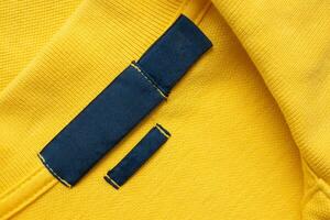 blanco blauw wasserij zorg kleren etiket Aan geel overhemd kleding stof structuur achtergrond foto