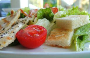 klein toast, eieren en voor de helft een tomaat met geraspt kaas Aan een salade bord foto