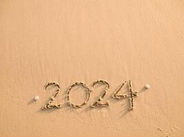2024 jaar geschreven Aan de strand in de zonsondergang tijd. nieuw jaar 2024 concept foto