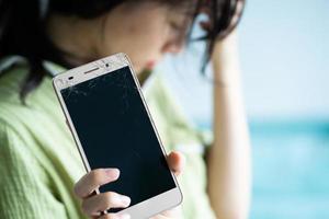 Aziatisch meisje voelt zich verdrietig omdat haar telefoon kapot is foto