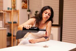 vrouw drinken wijn alleen gedurende een leven crisis. ongelukkig persoon ziekte en ongerustheid gevoel uitgeput met hebben alcoholisme problemen. foto