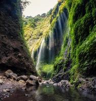 prachtige madakaripura-waterval die in groene vallei stroomt foto