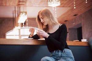 lachende vrouw in café met behulp van mobiele telefoon en sms'en in sociale netwerken, alleen zittend
