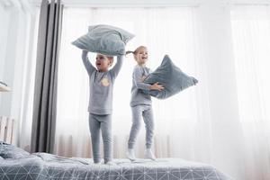 kinderen in zachte warme pyjama's die in bed spelen foto