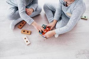 kinderen spelen met een speelgoedontwerper op de vloer van de kinderkamer. twee kinderen spelen met kleurrijke blokken. educatieve spelletjes voor de kleuterschool foto