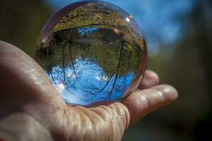 hand- Holding glas bal met omgekeerd natuur en landschap beeld foto
