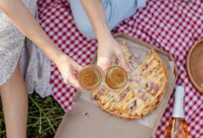 jong koppel met picknick op zonnebloemveld bij zonsondergang foto