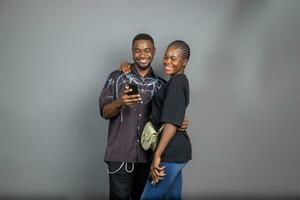 foto van positief opgewonden mensen Mens en vrouw glimlachen en op zoek Bij hun mobiel telefoons geïsoleerd over- grijs achtergrond