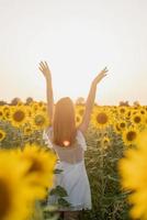 jonge mooie vrouw tussen zonnebloemen in zonsondergang foto