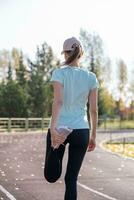 een jong mooi vrouw in sportkleding Toneelstukken sport- Bij een lokaal stadion foto