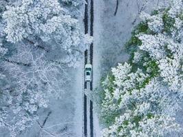 uitzicht op de witte auto van bovenaf in bevroren winterbos foto