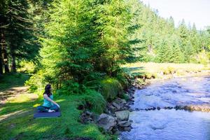 vrouw doet yoga op rivierstrand foto