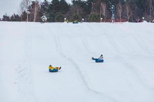 mensen die op snowtubing rijden in het winterpark foto