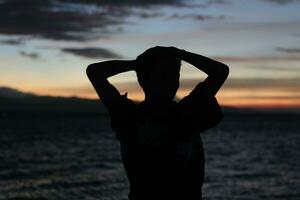 silhouet van een jong Mens staand door de meer genieten van de zonsondergang. vredig atmosfeer in natuur foto