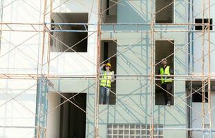 ingenieur en architect werken Aan de bouw plaats, dubbel checken plannen en werkwijze. foto