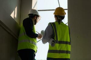 ingenieur en architect werken Aan de bouw plaats, dubbel checken plannen en werkwijze. foto