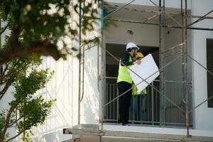 ingenieur en architect werken Aan de bouw plaats, dubbel checken plannen en werkwijze. foto