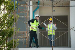 ingenieur en architect werken Aan de bouw plaats, dubbel checken plannen en werkwijze. foto