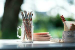 verf borstels in glas pot Aan houten tafel in de tuin voor voorbereidingen treffen naar verf pottenbakkerij. foto