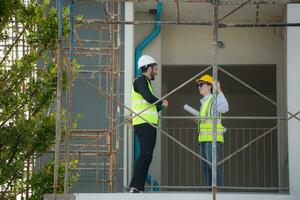 ingenieur en architect werken Aan de bouw plaats, dubbel checken plannen en werkwijze. foto