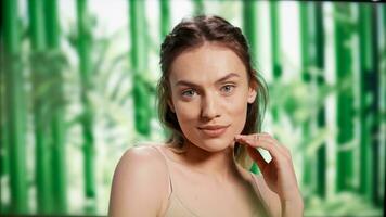 glimlachen vlekkeloos vrouw met kaal lichtgevend huid poseren Aan camera, staand over- achtergrond met bamboe bomen. gelukkig mooi meisje bevorderen schoonheidsmiddelen en huidsverzorging routine- in studio. foto