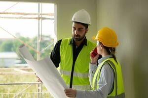 ingenieur en architect werken Aan de bouw plaats, dubbel checken plannen en werkwijze. foto