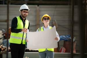 ingenieur en architect werken Aan de bouw plaats, dubbel checken plannen en werkwijze. foto